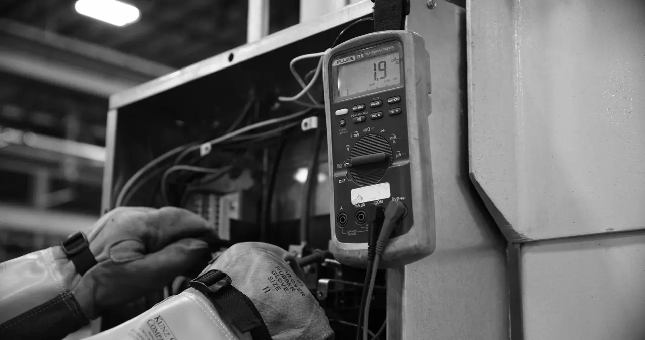 Técnico medindo um quadro elétrico com multímetro